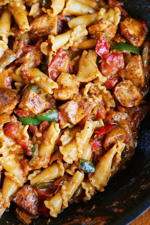 pasta with meat and vegetables in a skillet on a wooden table top, ready to be eaten