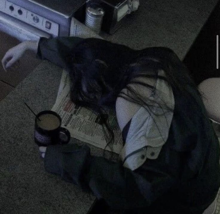 a woman laying on the floor with her head down next to a cup of coffee