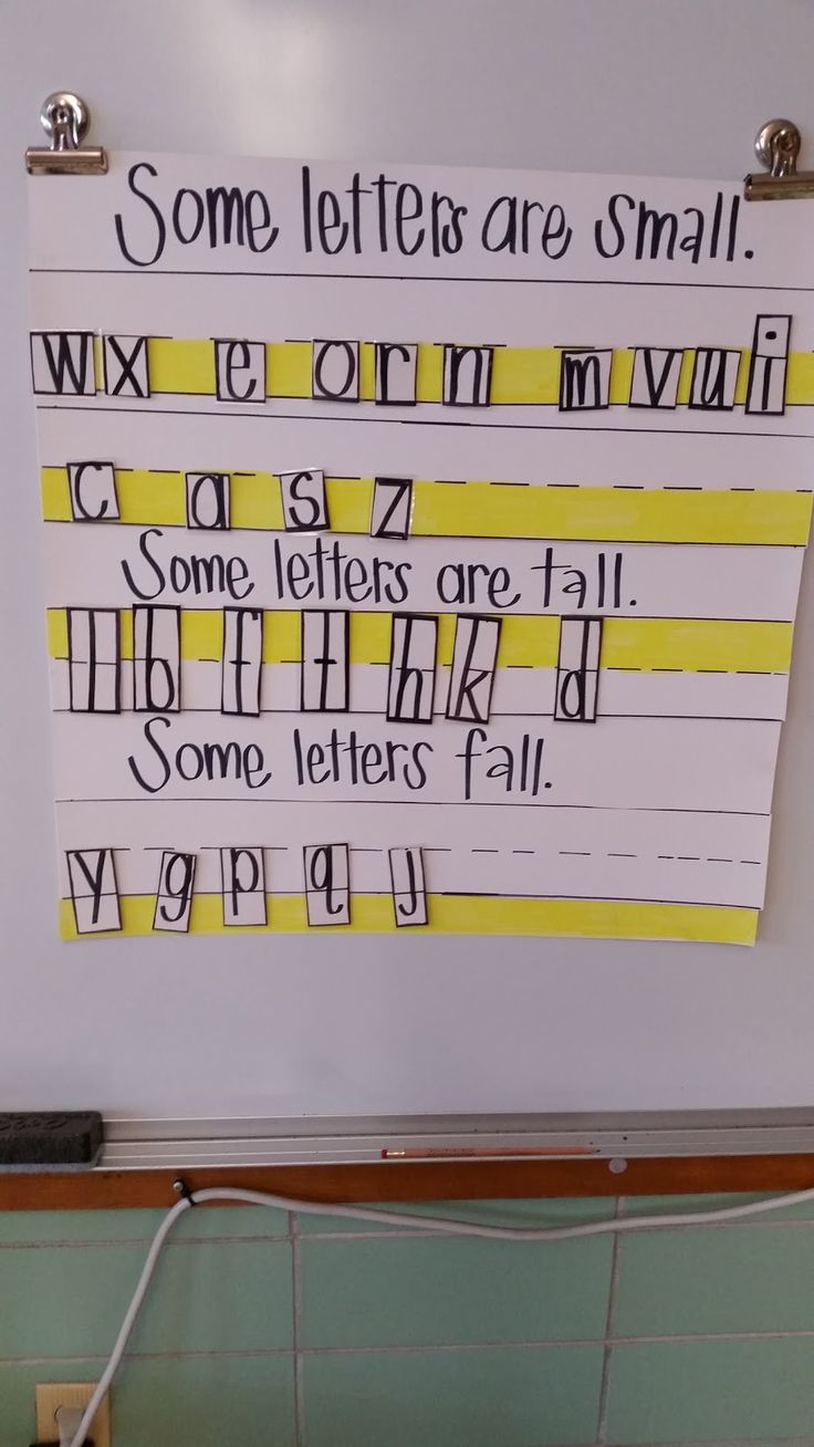 some letters are small written on a white board with yellow strips and black lettering in front of it