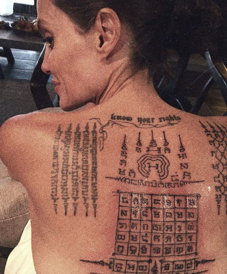 the back of a woman's upper body with tattoos on her chest and neck