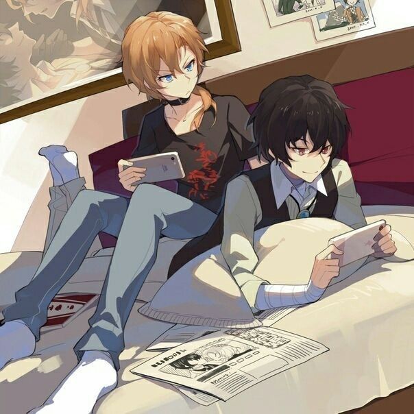 two people sitting on a bed with papers in front of them and one person reading