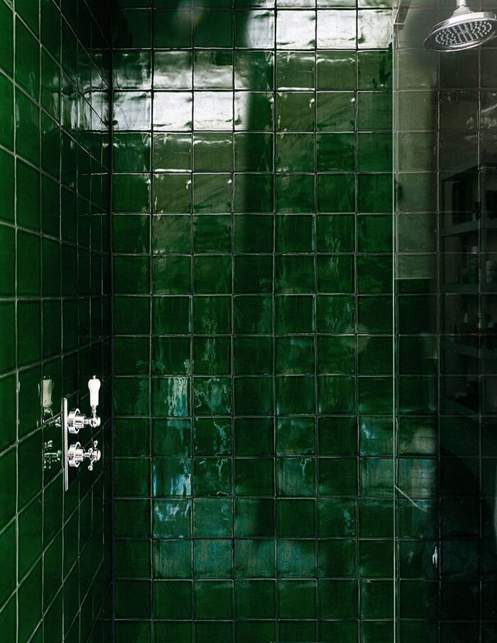 a green tiled bathroom with a shower head