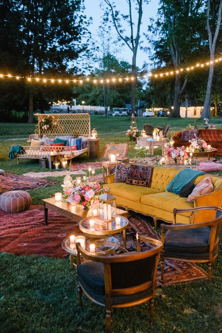 an outdoor seating area is lit up with string lights and decorated furniture for a party