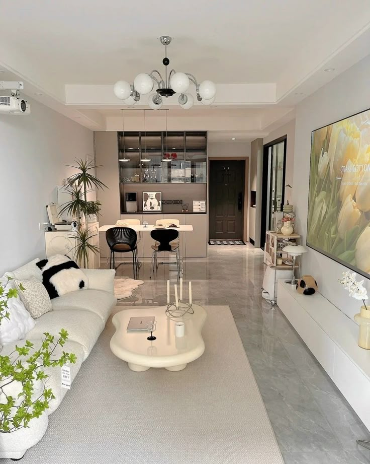 a living room filled with white furniture and lots of plants on top of the tables