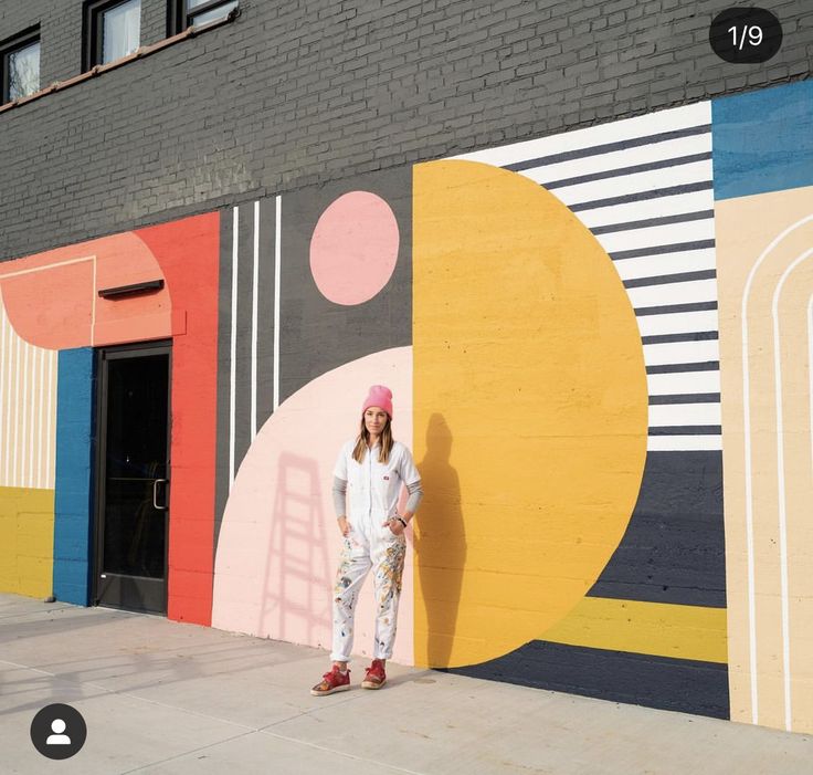 a woman standing in front of a colorful wall