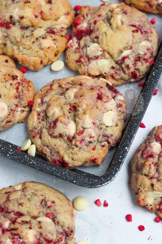 cookies with white chocolate chips and cranberries are on a baking sheet, ready to be eaten