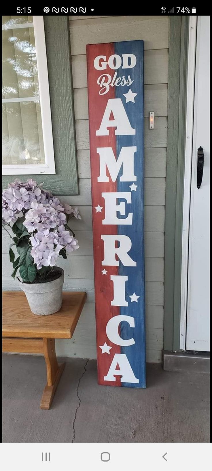 a red, white and blue sign sitting on the side of a house next to a potted plant