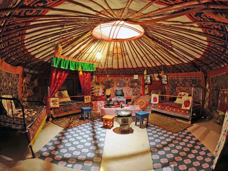 the inside of a yurt with several tables, chairs and rugs on the floor