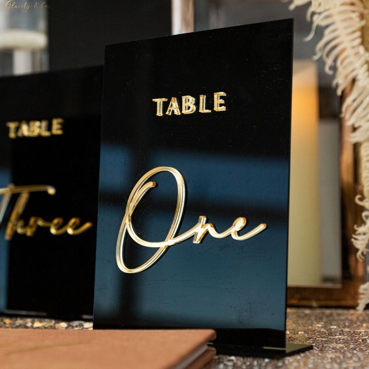 two black and gold table numbers are sitting on a counter top next to each other