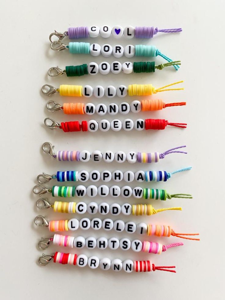 six key chains with the names of different colors and sizes are arranged on a white surface