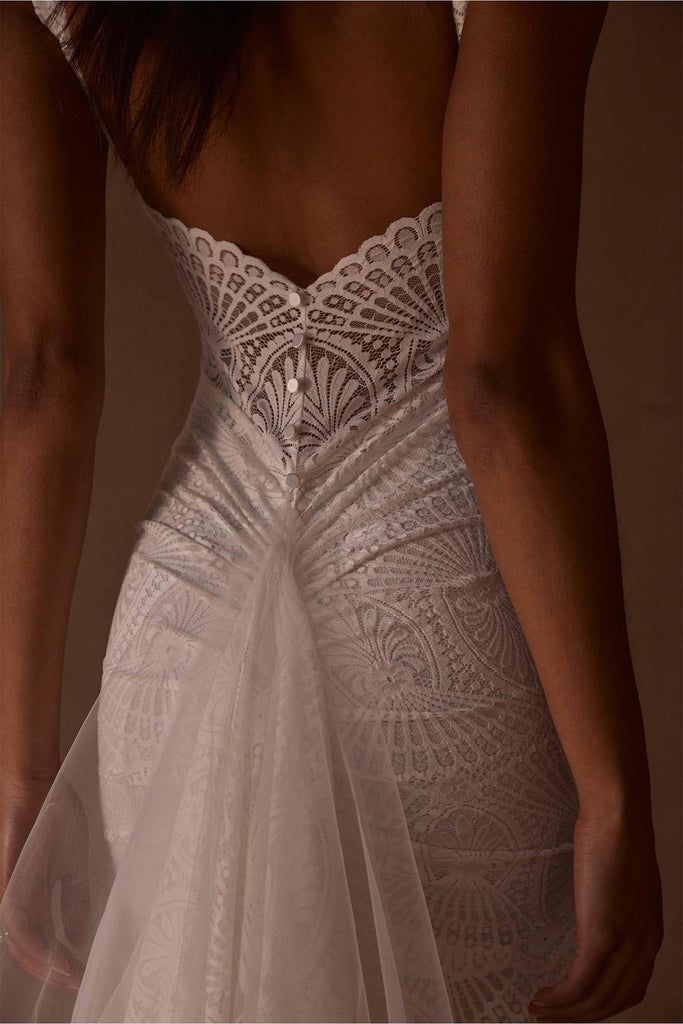 the back of a woman's wedding dress, with her hands on her hips