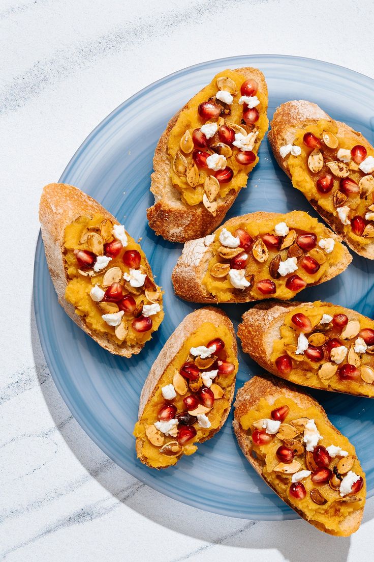 a blue plate topped with bread covered in toppings on top of a white table