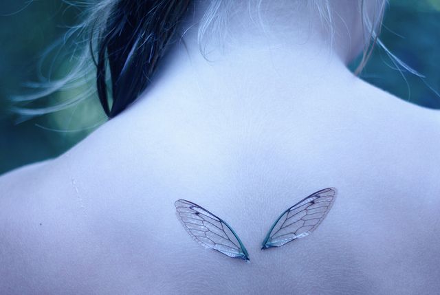 the back of a woman's neck with a butterfly tattoo on it