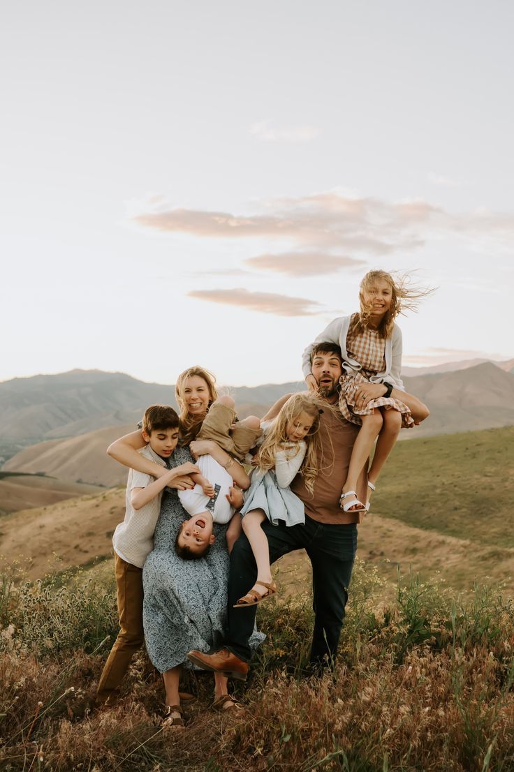 a group of people standing on top of a grass covered hillside