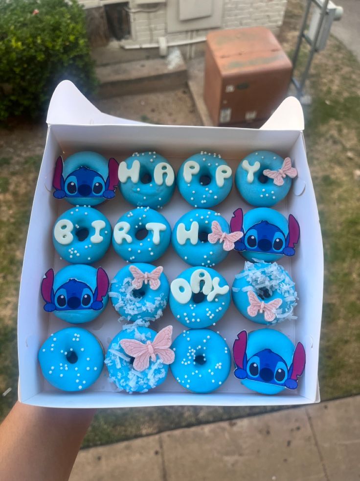 a box filled with blue frosted cupcakes sitting on top of a sidewalk