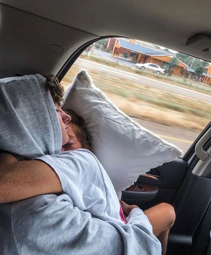 a man sleeping in the back seat of a car with his head on a pillow