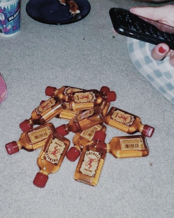 a pile of liquor bottles sitting on top of a floor next to a remote control