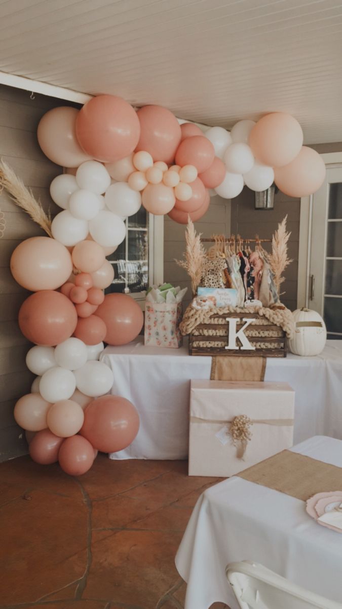 a table topped with lots of balloons next to a cake