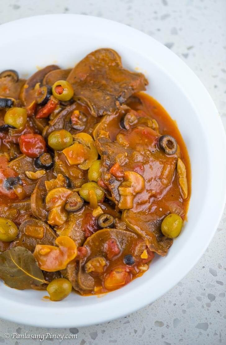 a white bowl filled with stew and olives