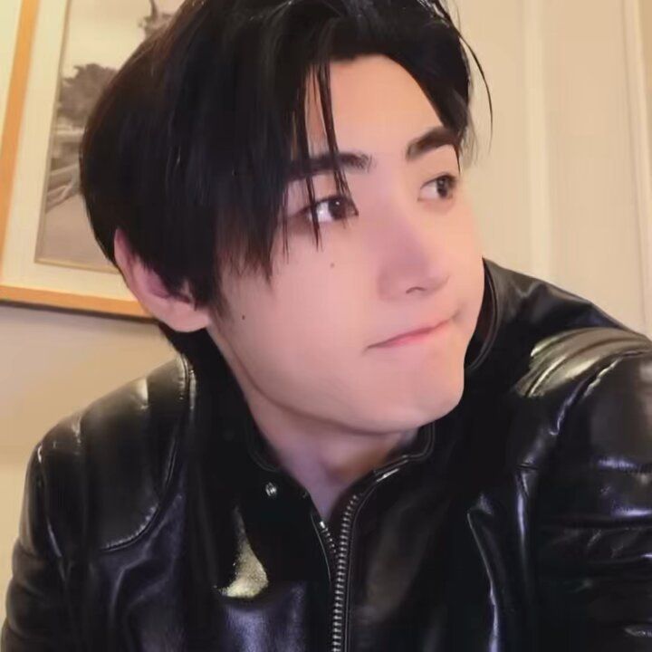 a man with black hair wearing a leather jacket