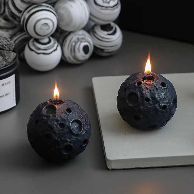 two black candles sitting on top of a white plate