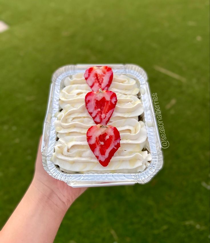 someone holding up a cake with strawberries in the shape of hearts on it's side