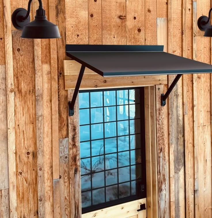 two black lights are hanging from the side of a wooden wall next to a window