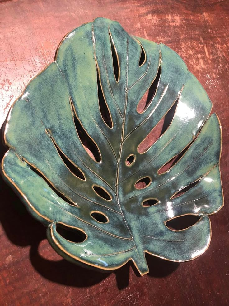 a green leaf shaped dish sitting on top of a wooden table