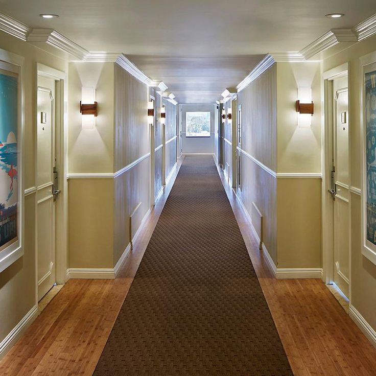 a long hallway with lights on both sides and carpeted flooring in between the two rooms