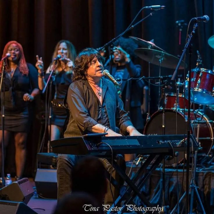 a group of people that are standing in front of a microphone and keyboard on stage