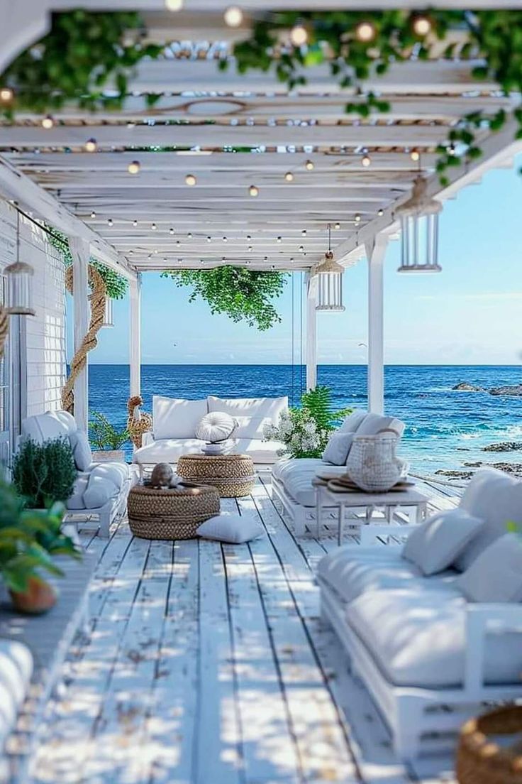 an outdoor living area with white furniture and greenery on the roof over looking the ocean