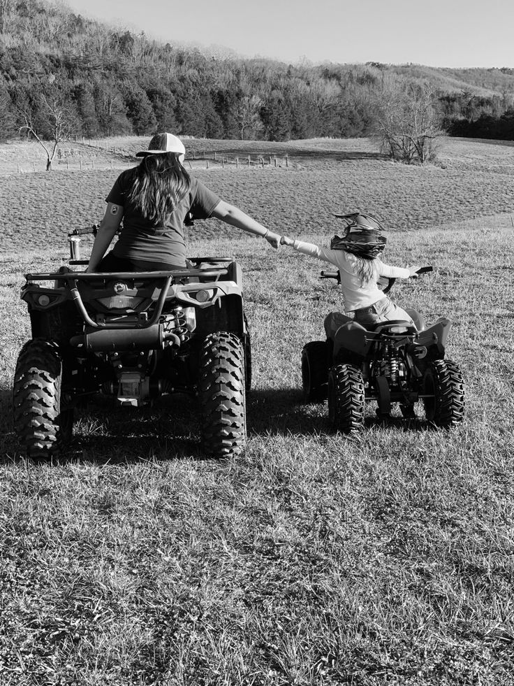 an adult and child riding on four wheelers