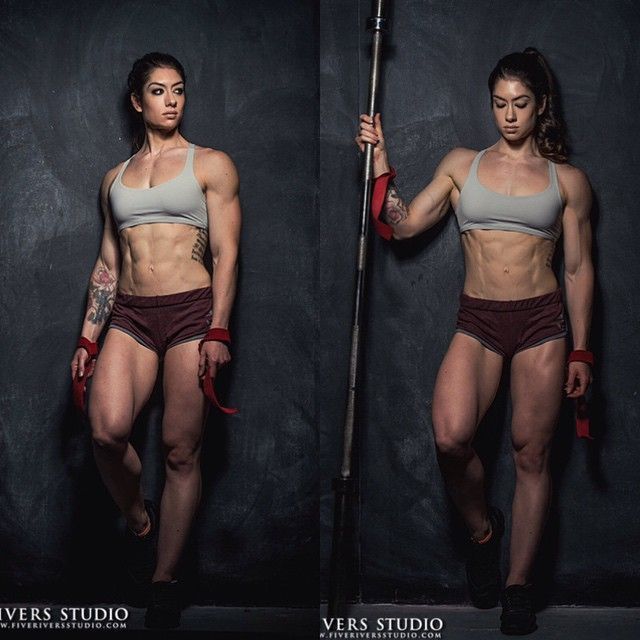 a woman with no shirt on holding a pole and posing for the camera in front of a black background