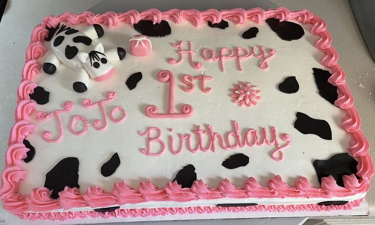 a birthday cake with pink frosting and black cow designs on it's icing