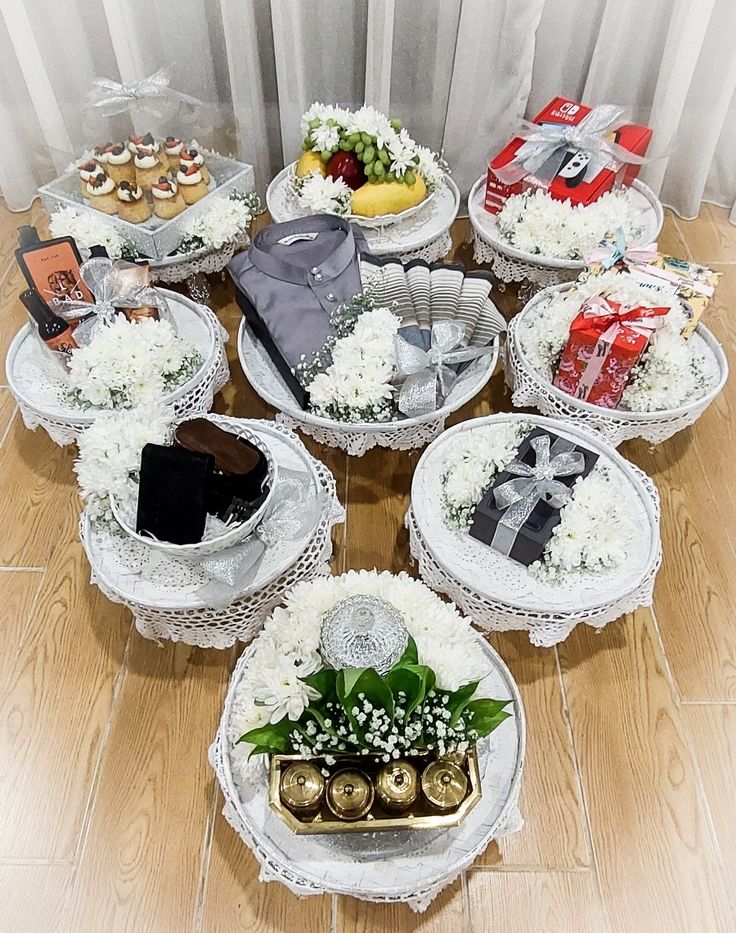 a table topped with lots of white plates filled with cakes and desserts next to a window