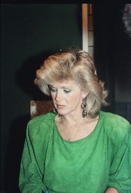 a woman sitting at a table in front of a plate of food and looking down