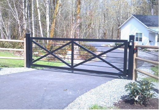 a gated driveway leading to a house in the woods