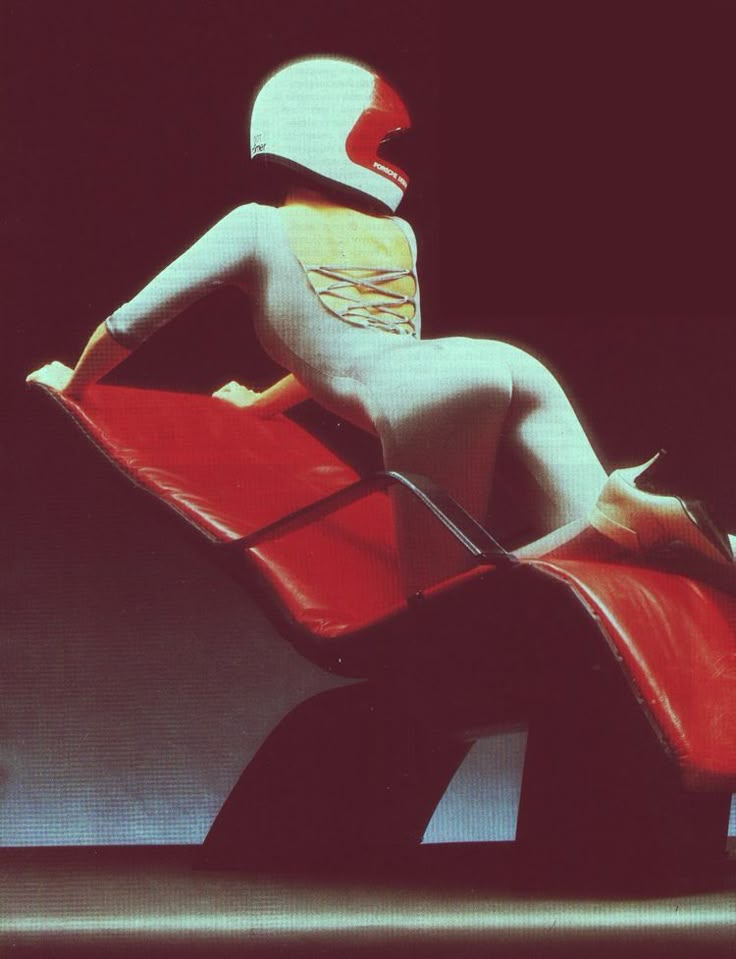 a person in a white bodysuit is sitting on a red chair and has his back turned to the camera