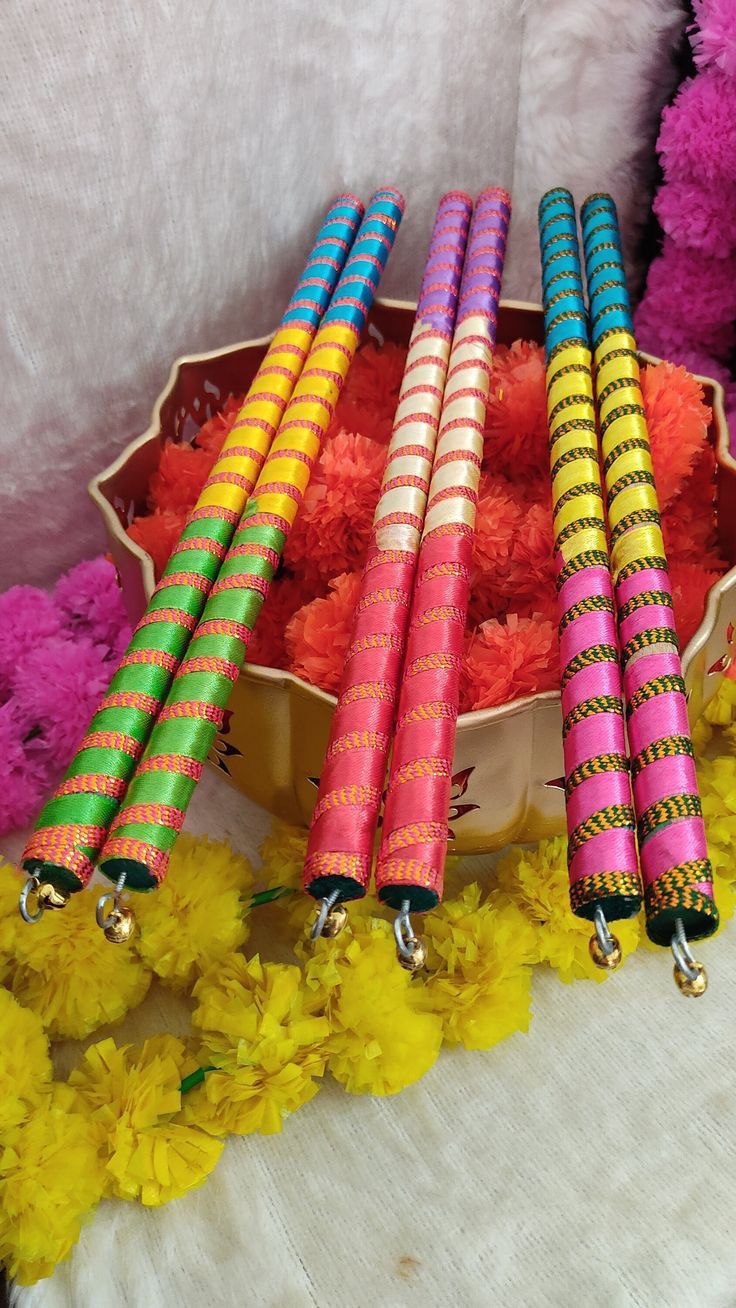 four colorful candles sitting in a bowl with flowers on the floor next to it and teddy bears behind them