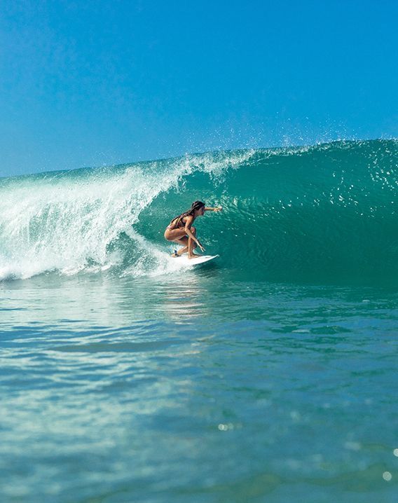 a person on a surfboard riding a wave in the ocean with clear blue skies