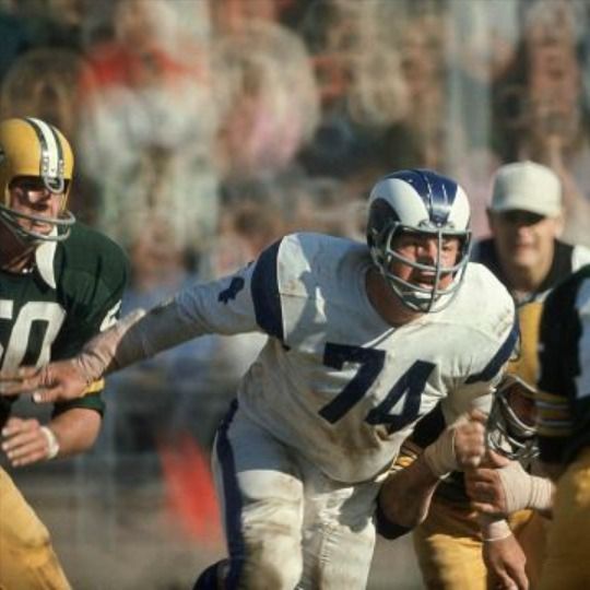 a football player is running with the ball in his hand and other players behind him