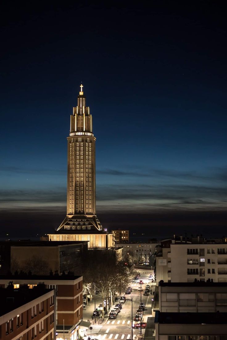 a very tall building with a clock on it's side at night time in the city