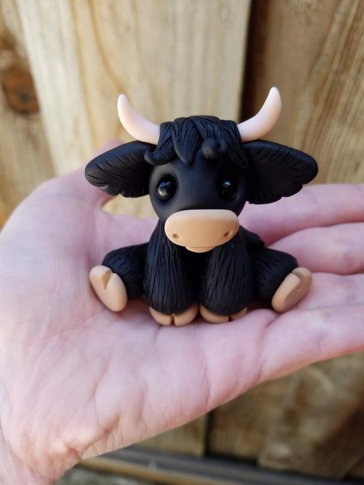 a small toy cow sitting on top of someone's hand