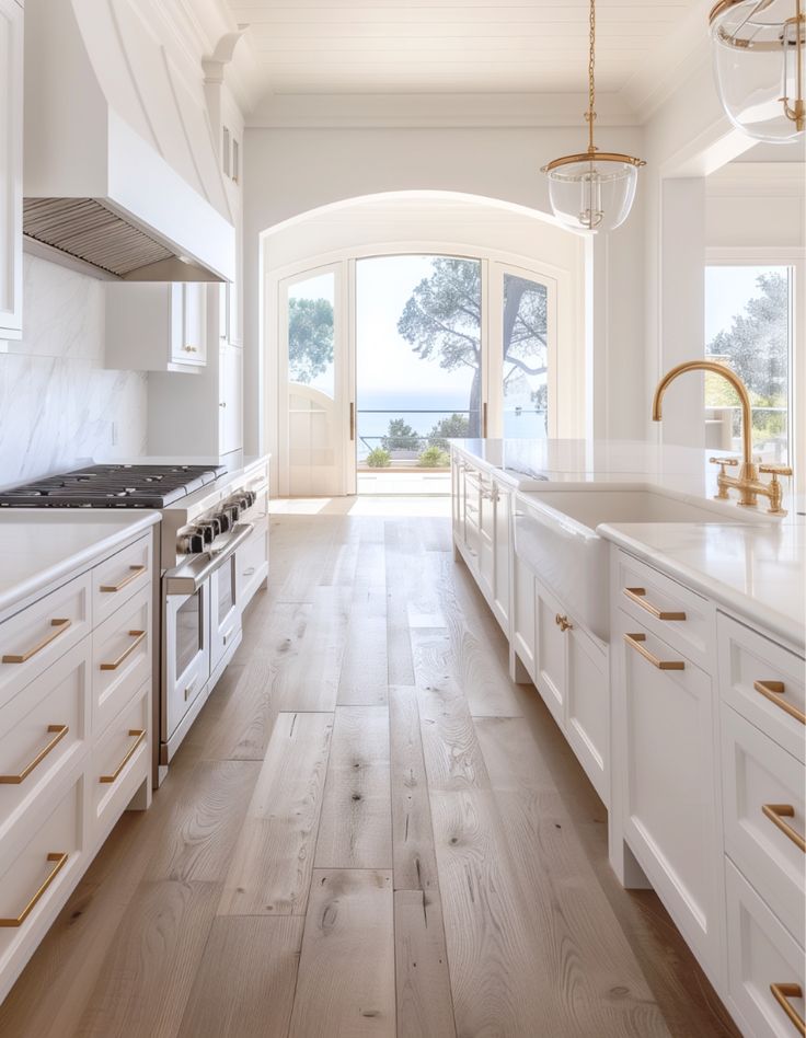 an open kitchen with white cabinets and wood flooring, along with a large window overlooking the ocean