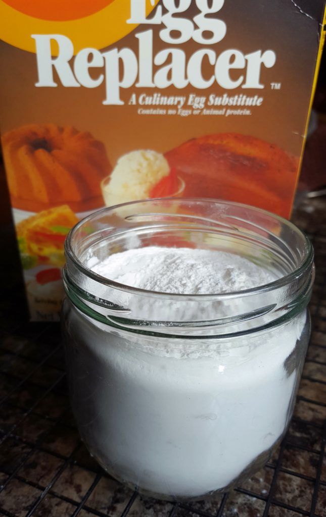 a glass jar filled with white powder next to a box of egg replacer on a table