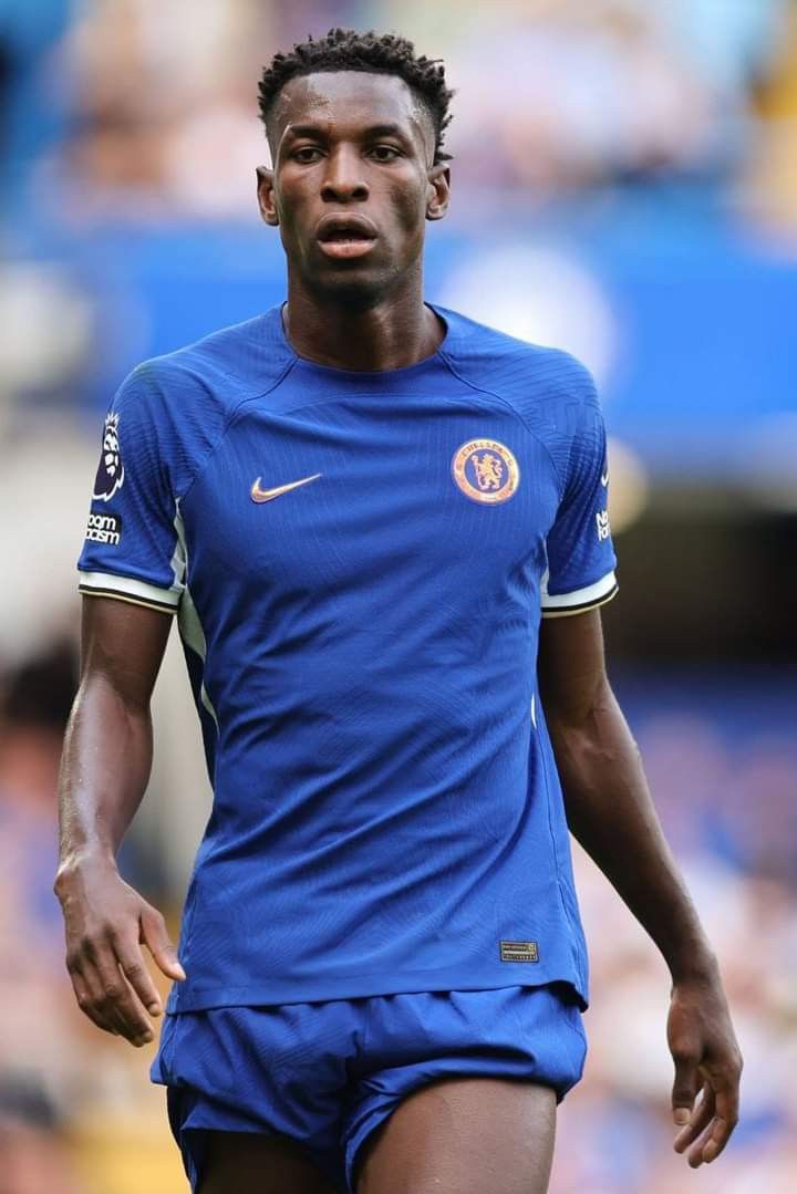 a soccer player in blue is looking at the ball while onlookers watch