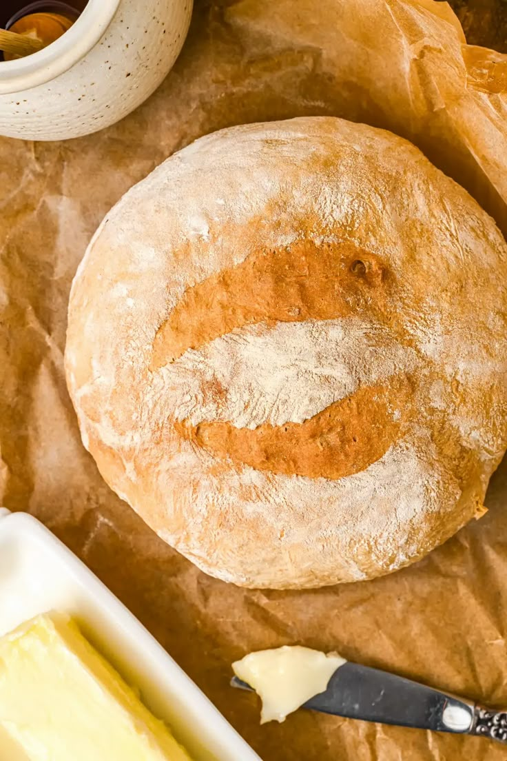 a loaf of bread sitting on top of a piece of wax paper next to butter