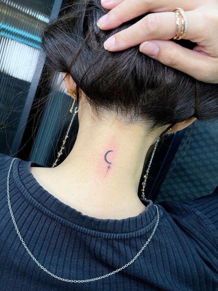 a woman with a small crescent tattoo on her neck