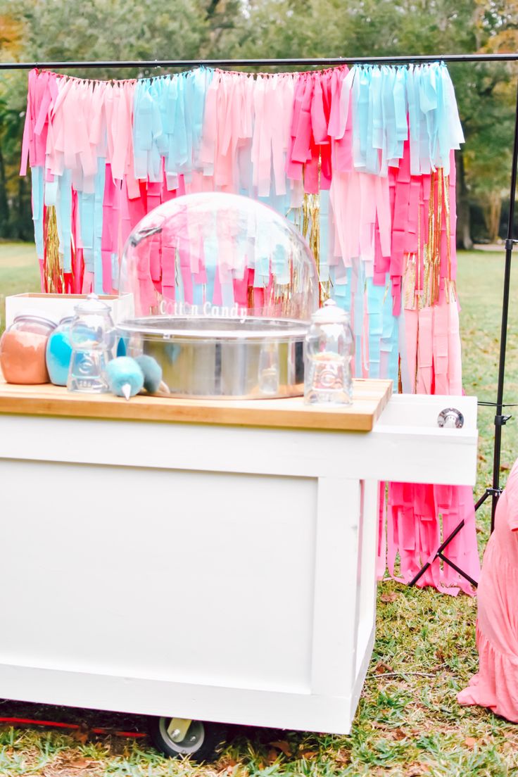 an ice cream cart with pink, blue and orange streamers on it's sides