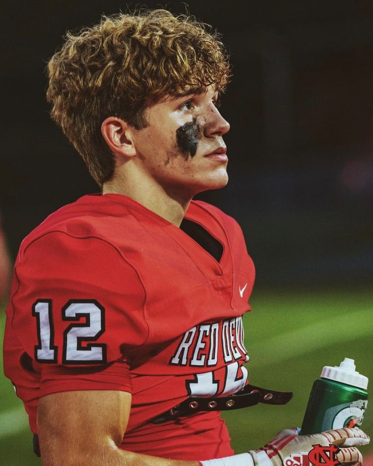 a man with his face painted like a football player holding a drink in one hand